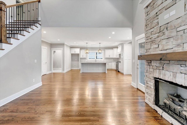 unfurnished living room featuring a stone fireplace and wood-type flooring