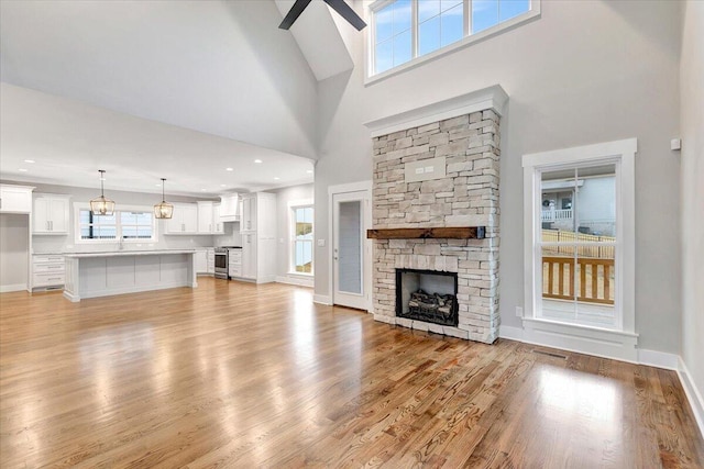 unfurnished living room featuring a towering ceiling, a fireplace, and light wood-type flooring