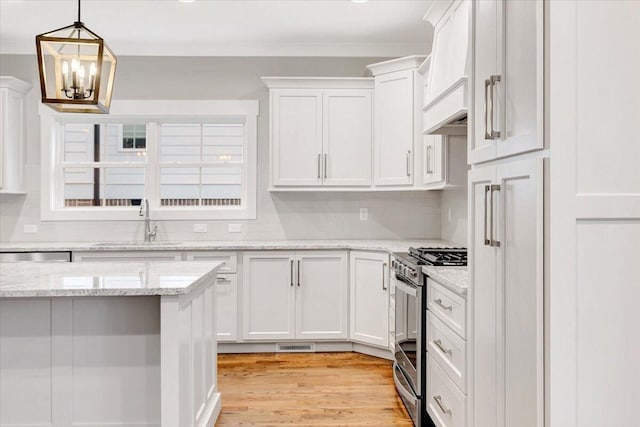 kitchen with white cabinets, light stone counters, light hardwood / wood-style flooring, sink, and stainless steel appliances