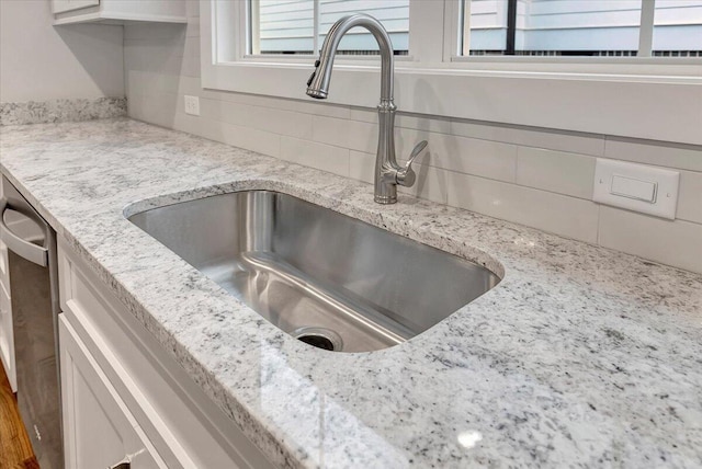 details with sink, light stone countertops, and decorative backsplash