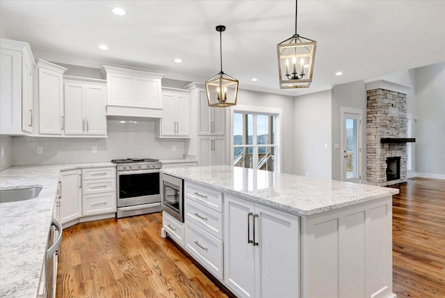 kitchen with decorative backsplash, a kitchen island, white cabinets, custom exhaust hood, and stainless steel appliances