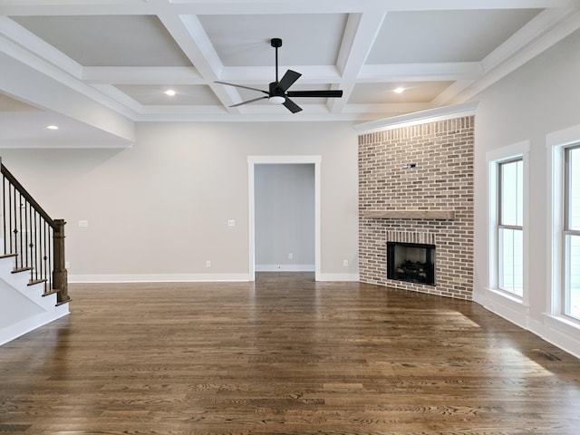 unfurnished living room featuring coffered ceiling, ceiling fan, a fireplace, beamed ceiling, and dark hardwood / wood-style flooring