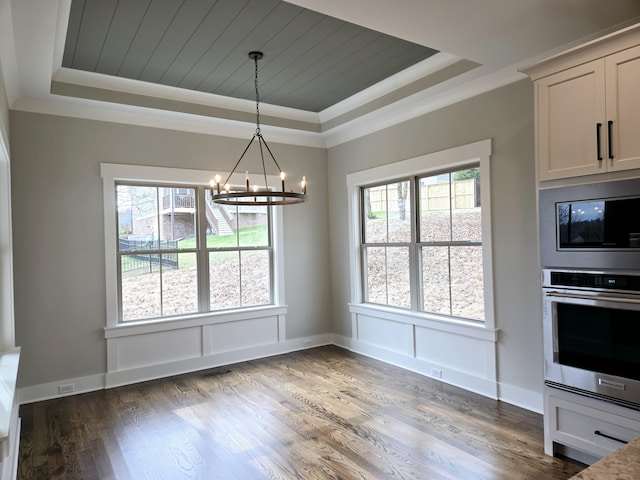 unfurnished dining area featuring a notable chandelier, a raised ceiling, ornamental molding, and dark wood-type flooring