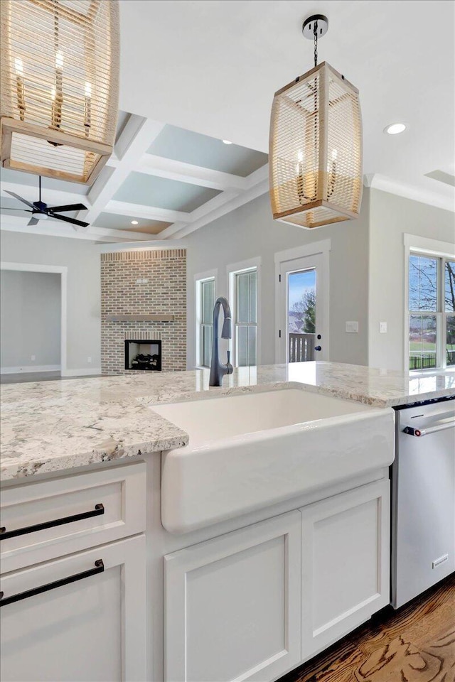 kitchen featuring decorative light fixtures, white cabinetry, sink, coffered ceiling, and stainless steel dishwasher