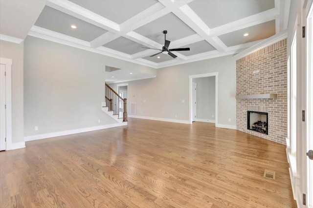 unfurnished living room with a fireplace, beamed ceiling, coffered ceiling, ceiling fan, and light hardwood / wood-style floors