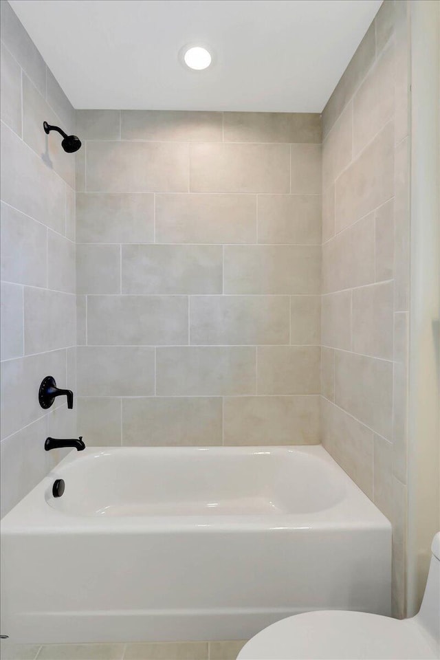 bathroom featuring toilet and tiled shower / bath combo