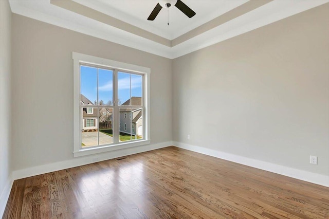 spare room with wood-type flooring, ceiling fan, and a tray ceiling