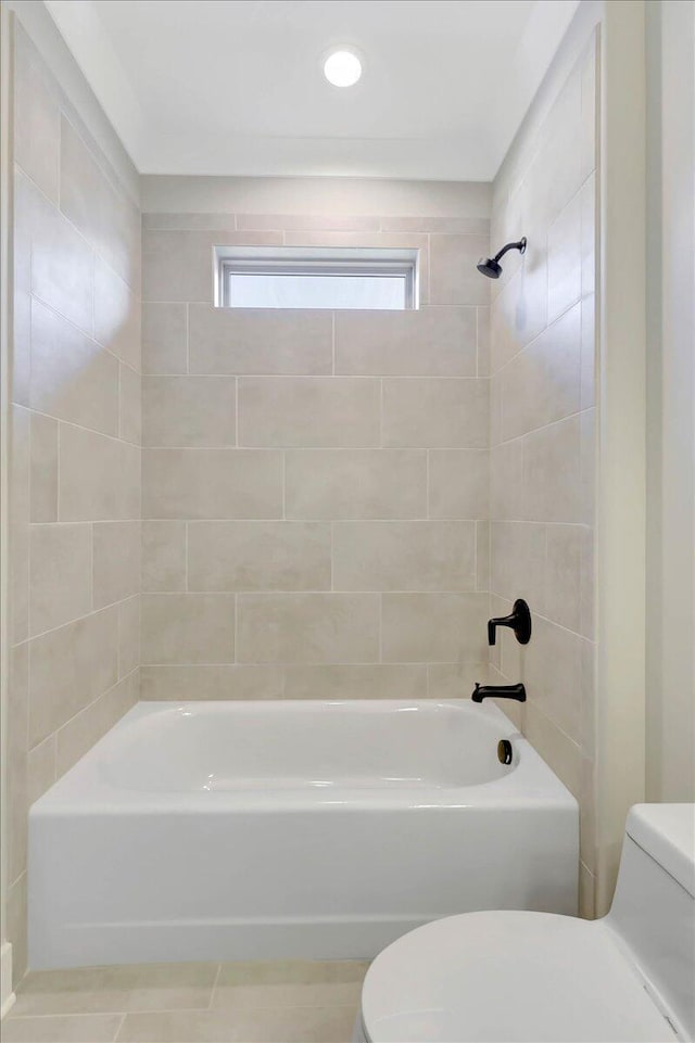 bathroom with tile patterned flooring, tiled shower / bath combo, and toilet