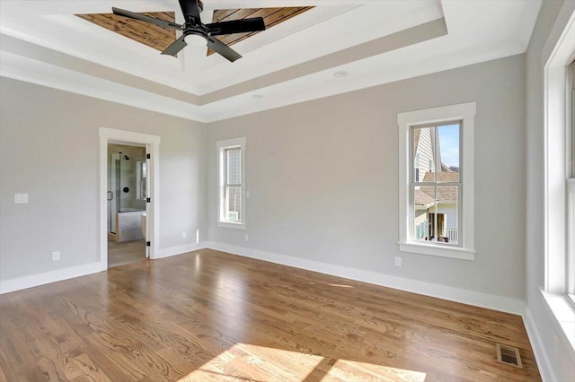 spare room with ceiling fan, a raised ceiling, and light hardwood / wood-style flooring