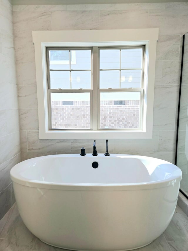 bathroom featuring tile walls and a tub