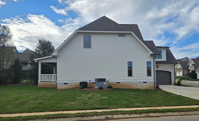 view of side of property featuring cooling unit, a yard, a garage, and covered porch