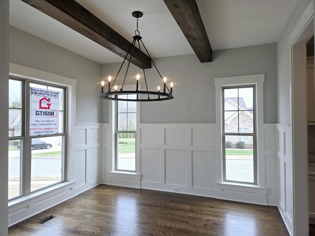 unfurnished dining area with an inviting chandelier, dark hardwood / wood-style floors, and beam ceiling