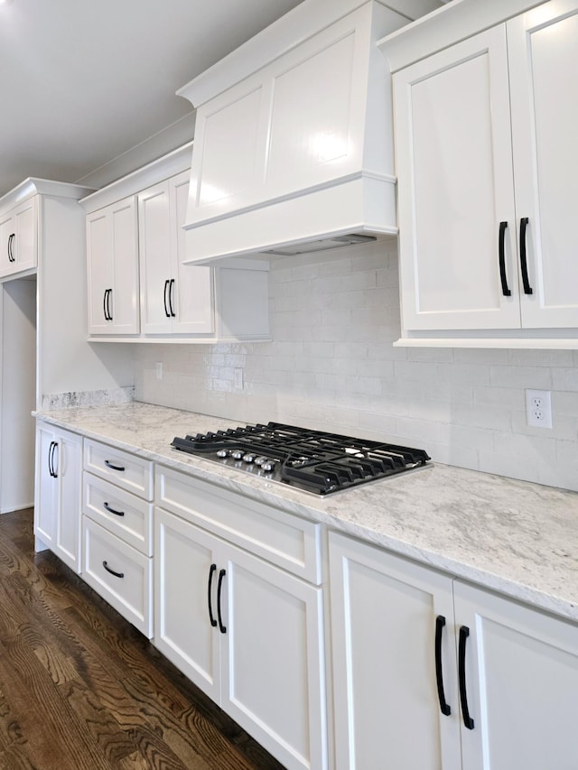 kitchen with dark wood-type flooring, light stone counters, tasteful backsplash, custom exhaust hood, and stainless steel gas stovetop