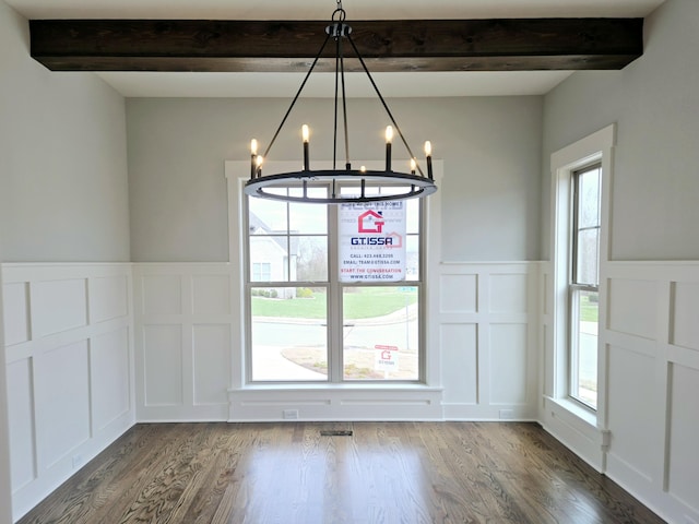 unfurnished dining area with an inviting chandelier, dark wood-type flooring, plenty of natural light, and beamed ceiling