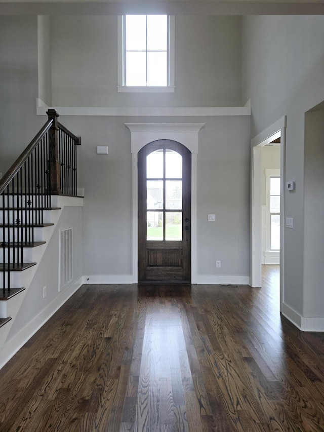 foyer with a towering ceiling and dark hardwood / wood-style flooring