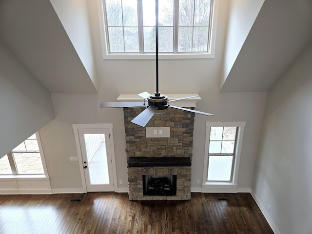 unfurnished living room featuring a high ceiling, a stone fireplace, and a healthy amount of sunlight