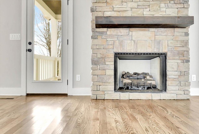 room details with hardwood / wood-style floors and a stone fireplace