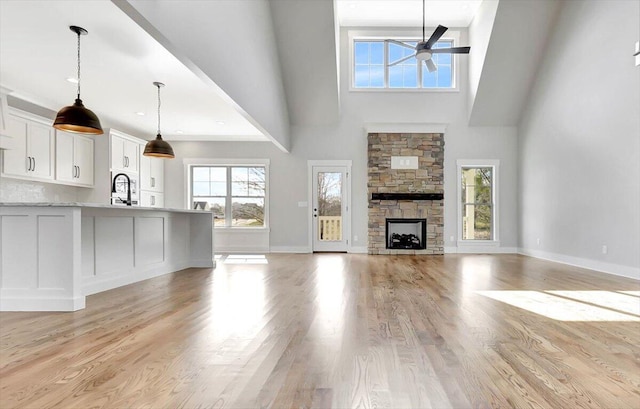 unfurnished living room with ceiling fan, a fireplace, light hardwood / wood-style floors, and a wealth of natural light