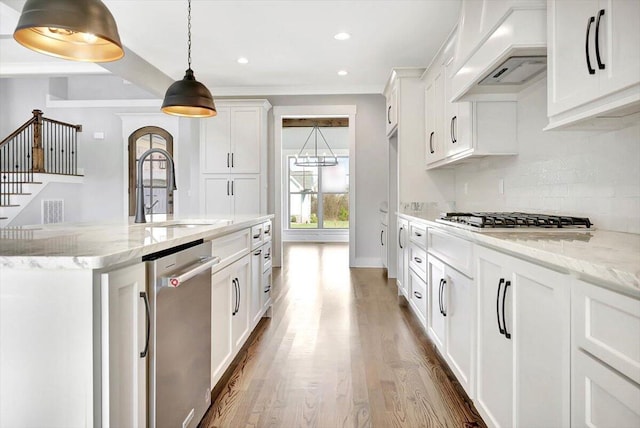 kitchen featuring sink, premium range hood, stainless steel appliances, white cabinets, and a kitchen island