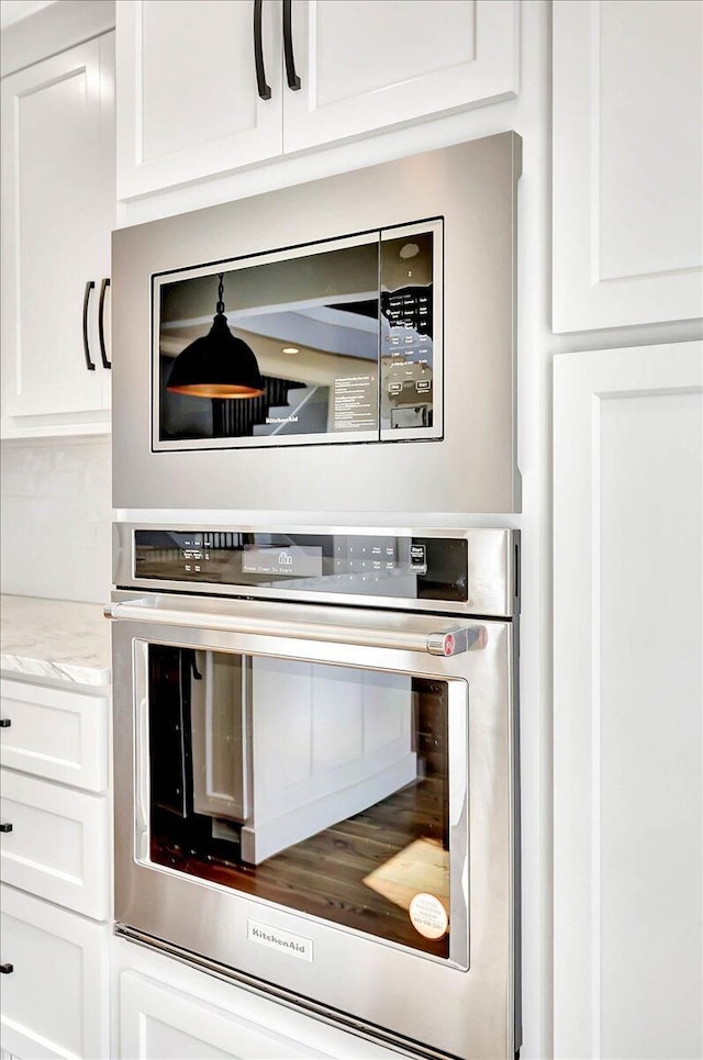 room details featuring light stone counters, appliances with stainless steel finishes, and white cabinets