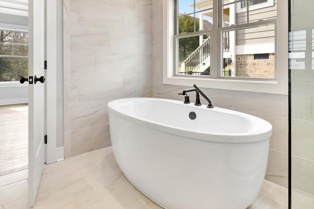 bathroom featuring tile walls and a tub to relax in