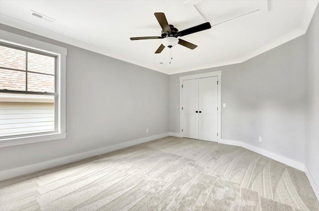 unfurnished bedroom featuring ceiling fan, a closet, ornamental molding, and light carpet