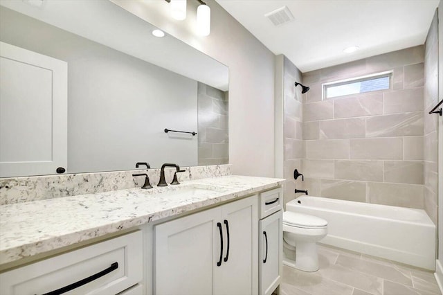 full bathroom with tiled shower / bath, vanity, and toilet