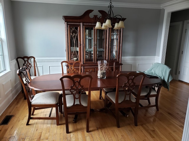 dining room with ornamental molding, a chandelier, and light hardwood / wood-style floors