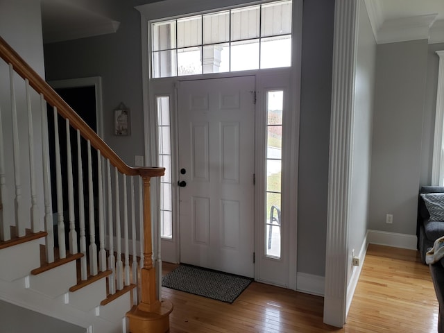 entrance foyer featuring light hardwood / wood-style floors, a healthy amount of sunlight, and crown molding