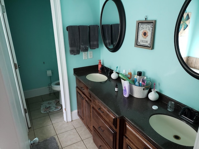 bathroom with toilet, vanity, and tile patterned floors