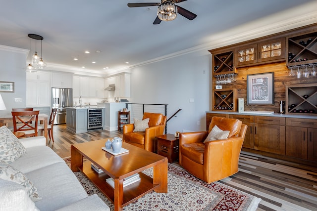 living room featuring sink, wine cooler, hardwood / wood-style flooring, ceiling fan, and ornamental molding