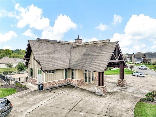 back of property featuring a chimney, board and batten siding, fence, a residential view, and stone siding