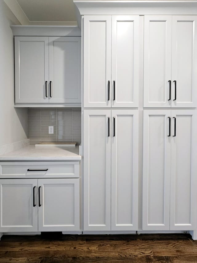 interior details featuring wood-type flooring and tasteful backsplash