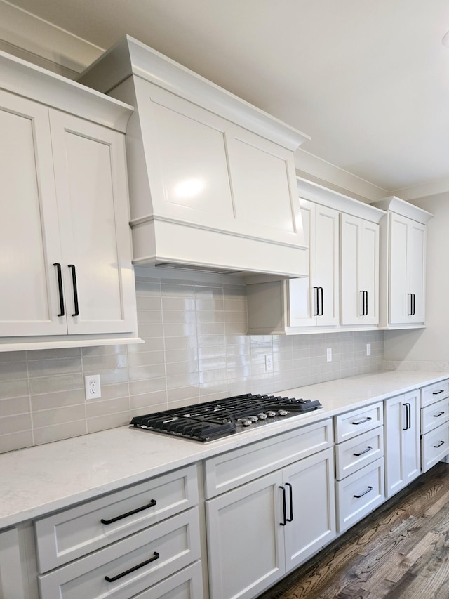 kitchen featuring tasteful backsplash, light stone counters, stainless steel gas cooktop, dark wood-type flooring, and white cabinetry