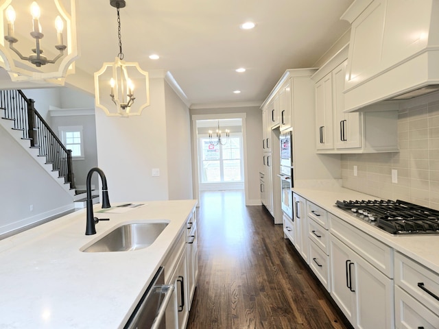 kitchen with sink, stainless steel appliances, decorative light fixtures, white cabinets, and custom range hood