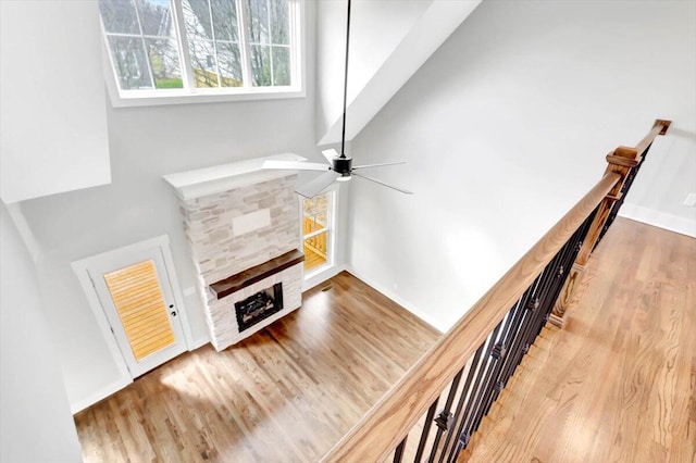 living room featuring ceiling fan, a fireplace, baseboards, and wood finished floors