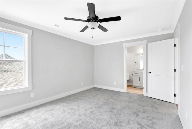 unfurnished bedroom featuring light carpet, baseboards, visible vents, ornamental molding, and ensuite bathroom