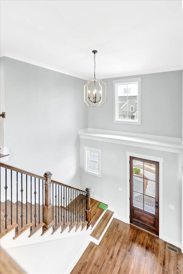 foyer featuring stairs, wood finished floors, visible vents, and a notable chandelier