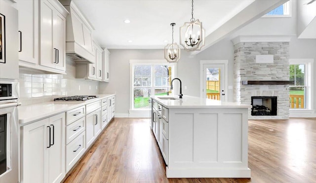 kitchen with light countertops, a sink, a kitchen island with sink, and decorative light fixtures