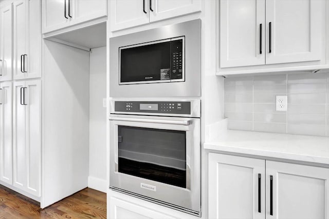 kitchen featuring light stone counters, stainless steel oven, white cabinetry, decorative backsplash, and built in microwave