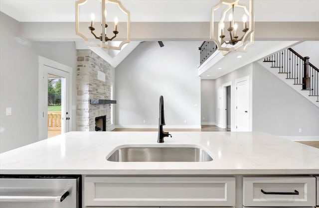 kitchen with pendant lighting, a fireplace, open floor plan, a sink, and a chandelier