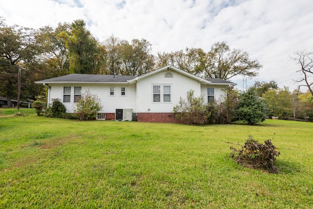 rear view of property featuring a yard and central AC unit