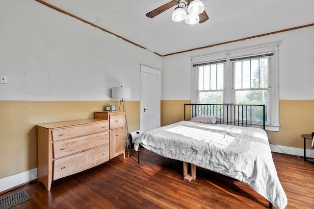 bedroom with dark wood-type flooring, crown molding, and ceiling fan