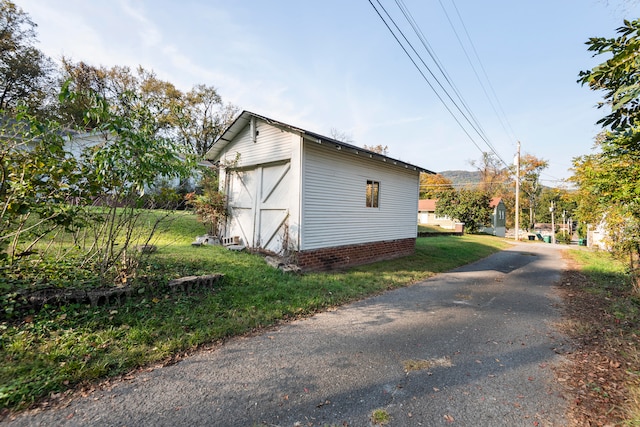 view of side of property with a storage shed and a lawn