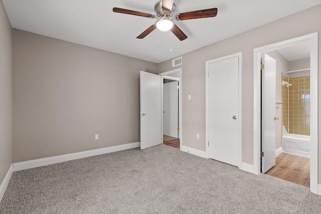 unfurnished bedroom with ceiling fan, light colored carpet, and ensuite bath