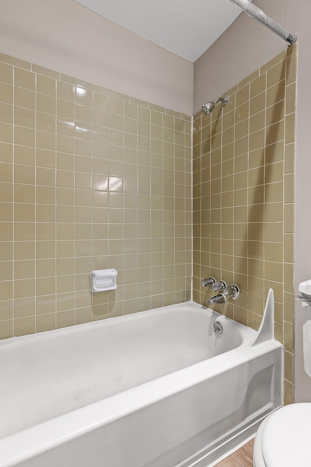 bathroom with tiled shower / bath combo and toilet