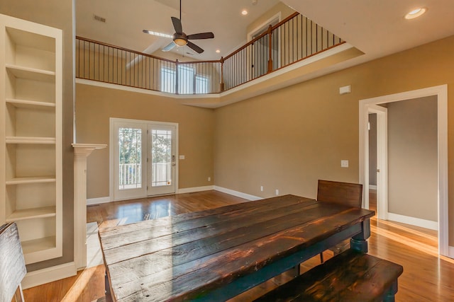 dining space featuring light hardwood / wood-style floors, a high ceiling, and ceiling fan