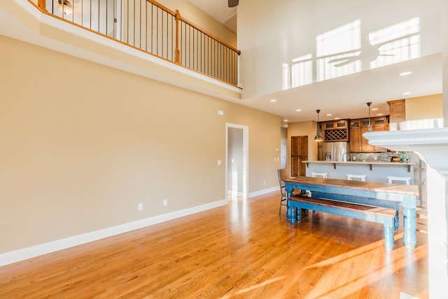 kitchen featuring kitchen peninsula, stainless steel fridge, ceiling fan, a high ceiling, and light hardwood / wood-style floors