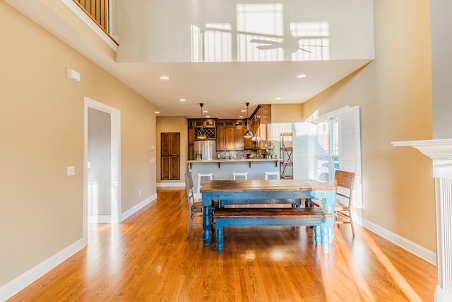 dining room with a high ceiling, light hardwood / wood-style floors, and ceiling fan