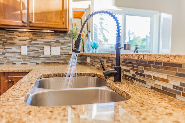 kitchen with sink, decorative backsplash, and light stone countertops